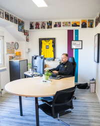 Ralf Feller in seinem Büro mit Erinnerungs-Fotos von Fußballprofis